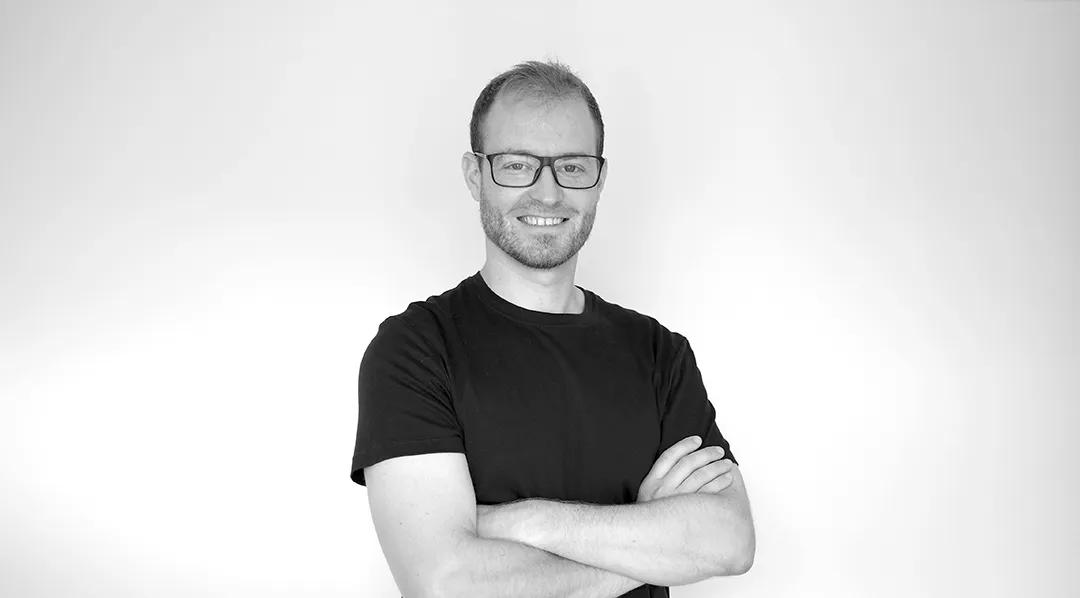 Jonny Marchbank, founder of Riptide Innovates, standing with his arms folded. Black and white portrait.