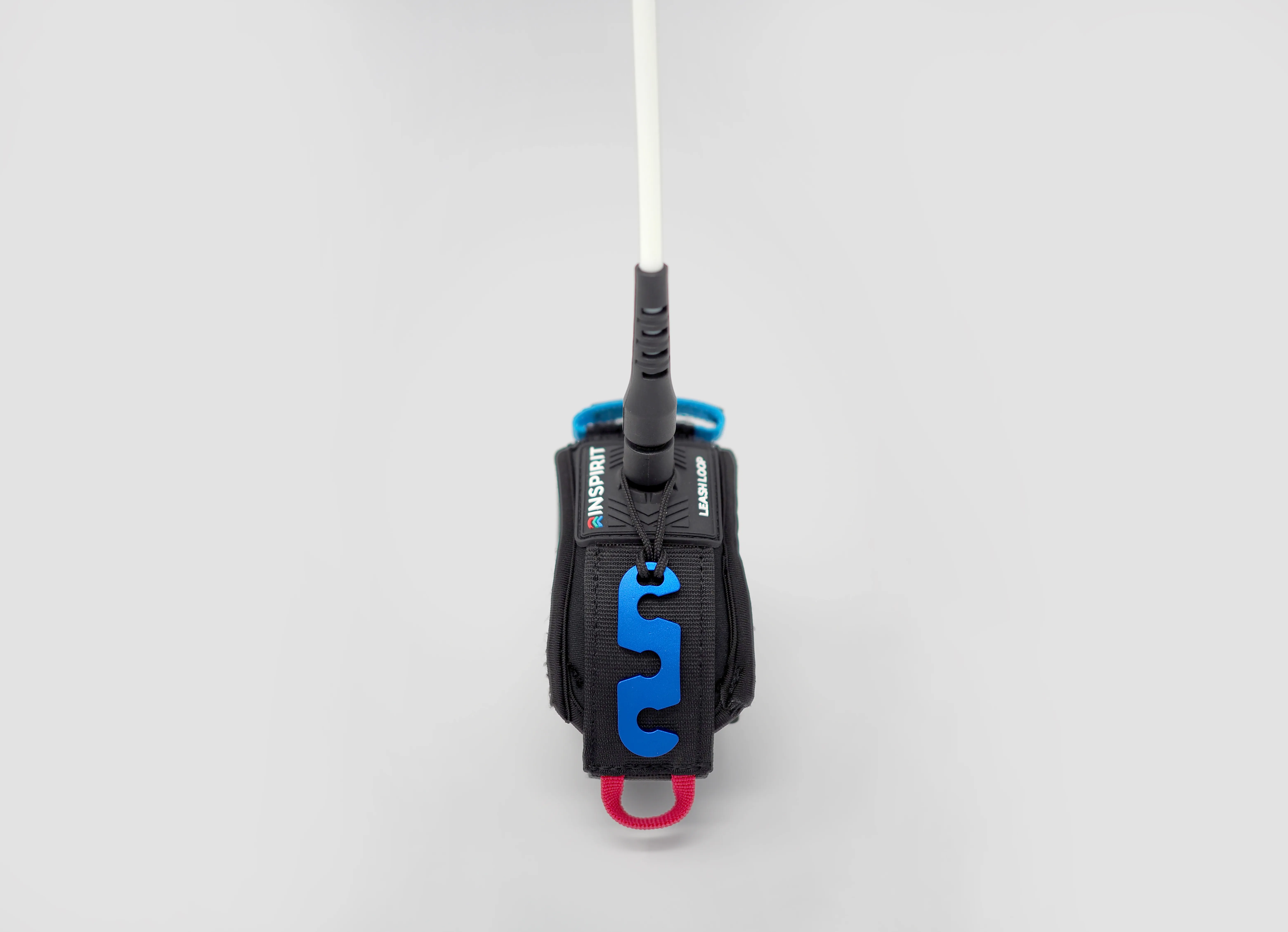 An Inspirit Adventure strap accessory in black, with blue and pink fittings, attached to a white pole.